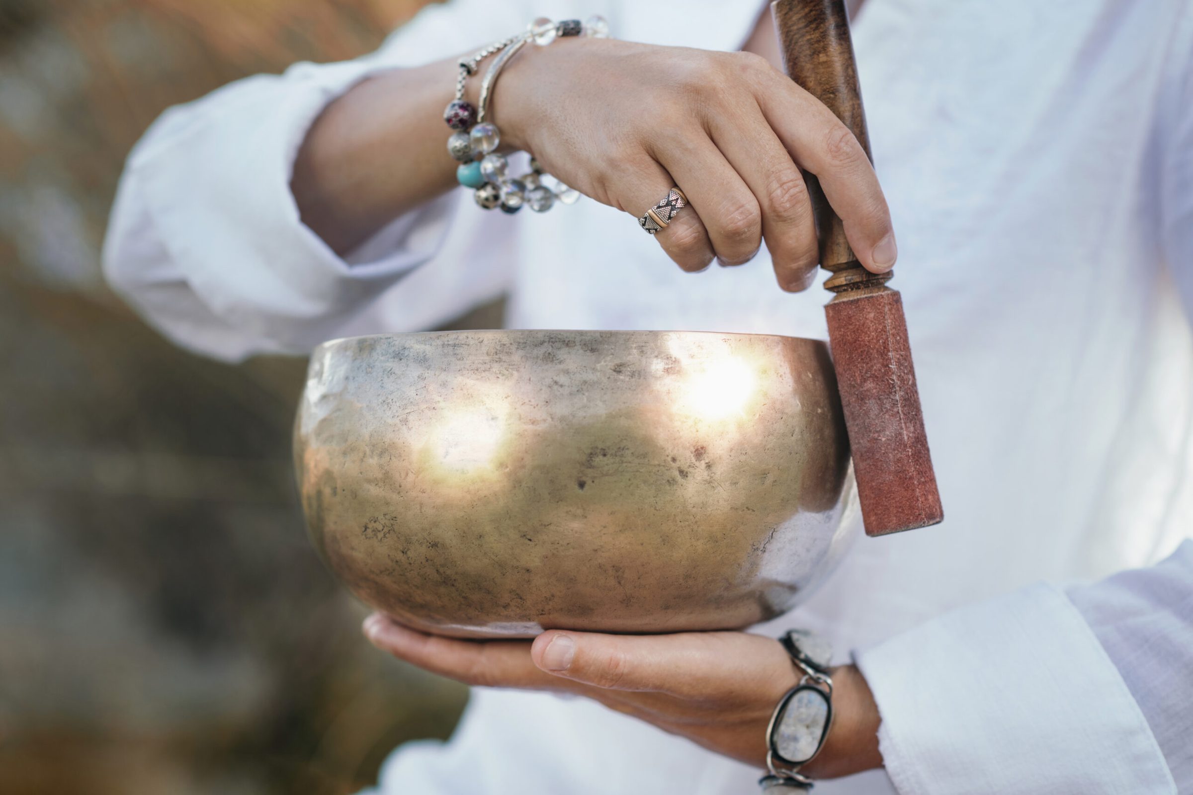 A practitioner holding a brass singing bowl during a sound session